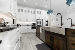 Kitchen featuring white cabinetry, dark brown cabinets, hanging light fixtures, and appliances with stainless steel finishes