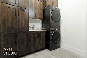 Clothes washing area with cabinets and stacked washer and clothes dryer