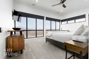 Carpeted bedroom with multiple windows and ceiling fan