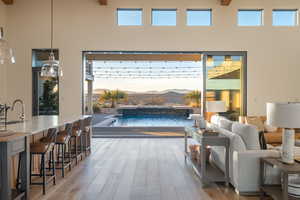 Living room featuring a mountain view, sink, a towering ceiling, and wood-type flooring