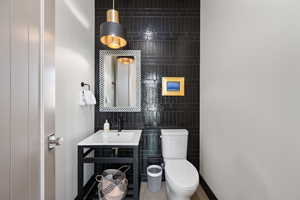 Bathroom featuring vanity, toilet, and tile walls