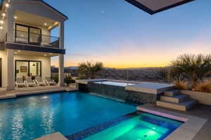 Pool at dusk with pool water feature, a patio area, and an in ground hot tub