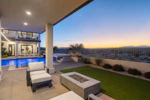 Pool at dusk featuring a patio area, an in ground hot tub, a mountain view, and an outdoor fire pit