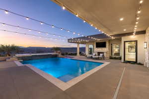 View of pool featuring an outdoor stone fireplace and a patio