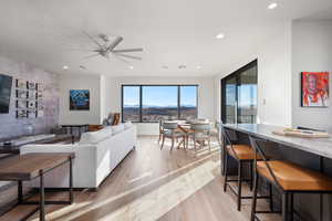 Living room with a mountain view, ceiling fan, and light hardwood / wood-style floors