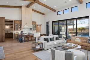 Living room featuring beam ceiling, a towering ceiling, and light wood-type flooring