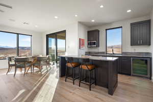 Kitchen with light stone countertops, beverage cooler, a mountain view, light hardwood / wood-style floors, and a kitchen island