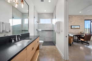 Bathroom featuring vanity, concrete floors, an enclosed shower, and toilet