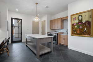 Kitchen with pendant lighting, a center island, sink, decorative backsplash, and a notable chandelier