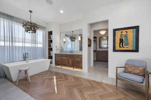 Bathroom featuring vanity, parquet flooring, a tub to relax in, and a chandelier