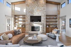 Living room with a towering ceiling, a fireplace, beamed ceiling, and hardwood / wood-style flooring