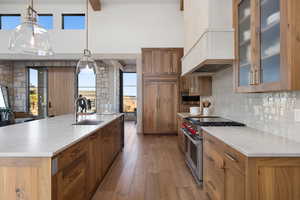 Kitchen featuring a large island with sink, premium appliances, hanging light fixtures, and sink