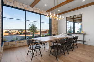 Dining area featuring beam ceiling, a chandelier, and light hardwood / wood-style floors