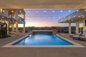 Pool at dusk featuring an in ground hot tub and a patio area