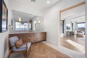 Bathroom featuring vanity, vaulted ceiling, and a notable chandelier