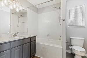 Full bathroom featuring hardwood / wood-style floors, vanity, tiled shower / bath combo, and toilet