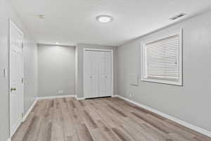 Unfurnished bedroom featuring light hardwood / wood-style floors, a textured ceiling, and a closet