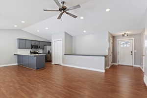 Kitchen with gray cabinetry, vaulted ceiling, stainless steel appliances, and dark wood-type flooring