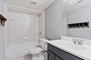 Full bathroom with tiled shower / bath, vanity, and toilet