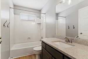 Full bathroom with hardwood / wood-style floors, vanity, toilet, and shower / tub combination