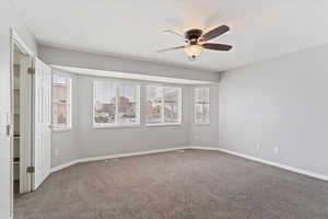 Empty room with plenty of natural light, ceiling fan, and carpet floors