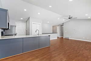 Kitchen featuring ceiling fan, sink, dark hardwood / wood-style flooring, kitchen peninsula, and vaulted ceiling