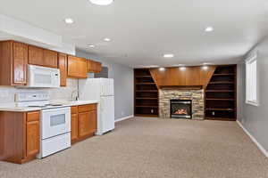 Kitchen with light carpet, white appliances, a fireplace, and sink