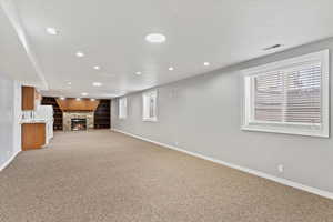 Unfurnished living room featuring carpet flooring, a stone fireplace, and sink