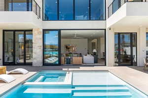 View of swimming pool with ceiling fan, a patio area, and an in ground hot tub