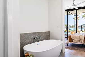 Bathroom featuring a bathing tub, ceiling fan, floor to ceiling windows, and hardwood / wood-style floors