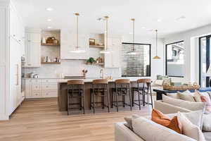 Kitchen with a breakfast bar area, white cabinetry, and pendant lighting