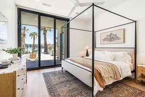 Bedroom featuring ceiling fan, a wall of windows, wood-type flooring, and access to outside