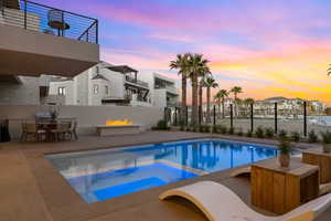 Pool at dusk with an in ground hot tub and a patio