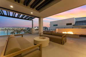 Balcony at dusk with a patio area, a water view, and an outdoor living space with a fire pit