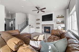 Living room with a fireplace, wood-type flooring, and ceiling fan