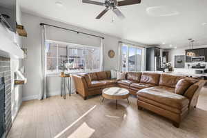 Living room with ceiling fan, a fireplace, a textured ceiling, and light hardwood / wood-style flooring