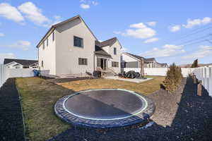 Rear view of house with a yard and a trampoline