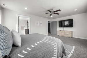 Carpeted bedroom featuring ceiling fan and ensuite bath