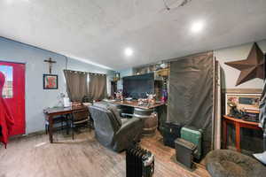 Office area with a textured ceiling, hardwood / wood-style floors, and lofted ceiling