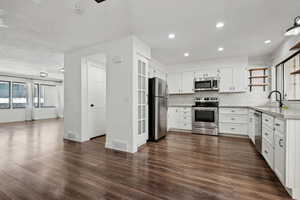 Kitchen featuring appliances with stainless steel finishes, backsplash, sink, dark hardwood / wood-style floors, and white cabinetry