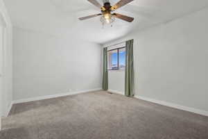 Carpeted spare room featuring ceiling fan