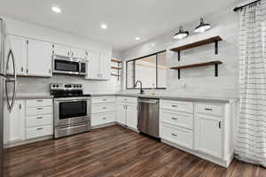 Kitchen with sink, decorative backsplash, appliances with stainless steel finishes, dark hardwood / wood-style flooring, and white cabinetry