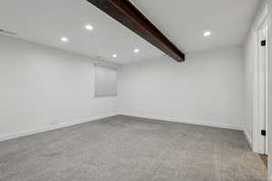 Empty room with beamed ceiling and carpet floors