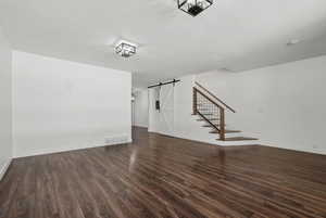 Unfurnished living room with dark hardwood / wood-style flooring and a barn door