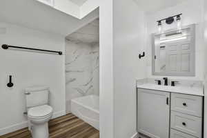 Full bathroom with hardwood / wood-style flooring, vanity, toilet, and tiled shower / bath combo