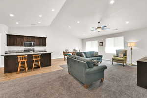 Living room featuring ceiling fan, sink, and lofted ceiling