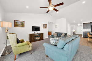 Living room featuring light wood-type flooring, vaulted ceiling, and ceiling fan