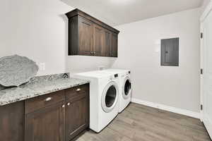 Laundry area featuring light hardwood / wood-style floors, cabinets, washing machine and dryer, and electric panel