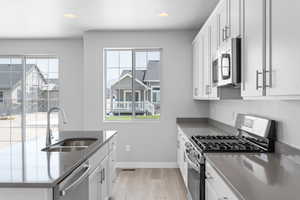 Kitchen featuring white cabinets, appliances with stainless steel finishes, light wood-type flooring, and sink