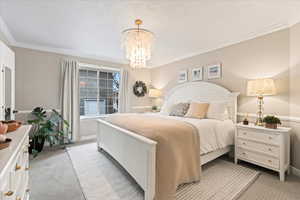 Carpeted bedroom with crown molding and a chandelier